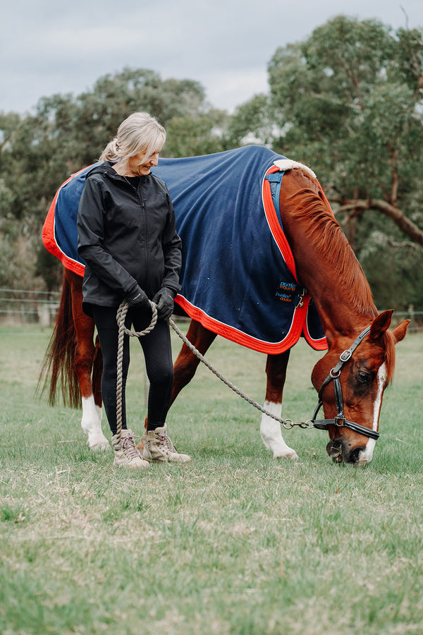 EQUICORE rider standing with a grazing chestnut horse