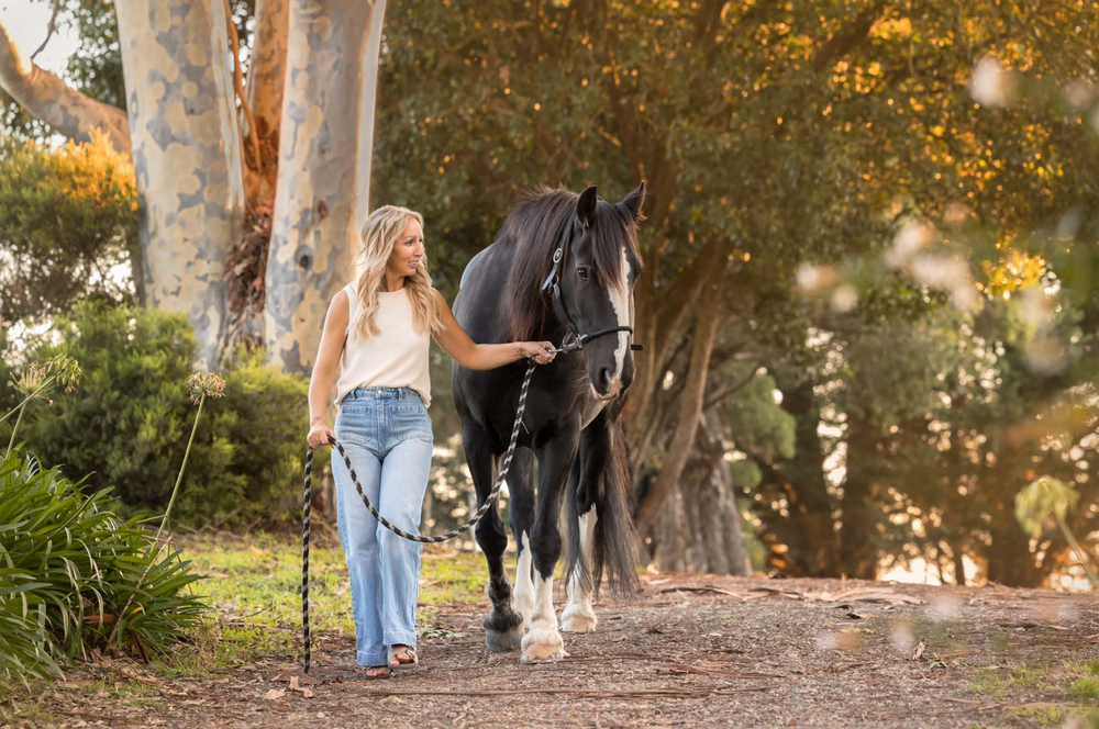 Rebecca walking with Jett beneath the trees