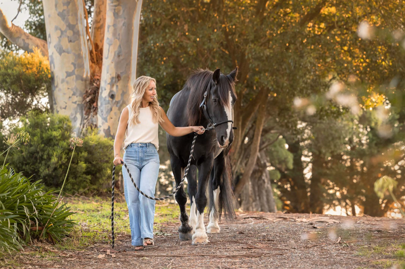 Rebecca walking with Jett beneath the trees